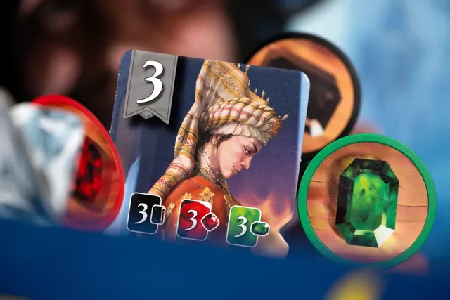 A level 3 card with a portrait of a noblewoman, beside a green emerald token