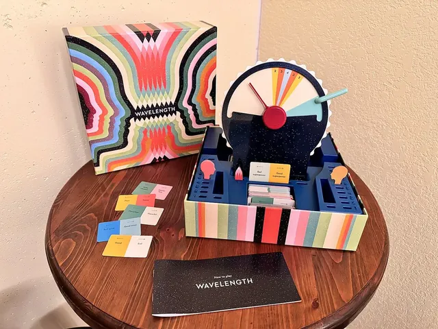 Wavelength set up at home on a round wooden table: the box, the device in its tray, spectrum cards and the rulebook