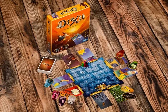 Dixit set up on a wooden table: the scoring track, rabbits, card piles and the box