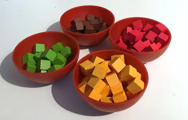 Spice cubes in yellow, red, green and brown in their bowls