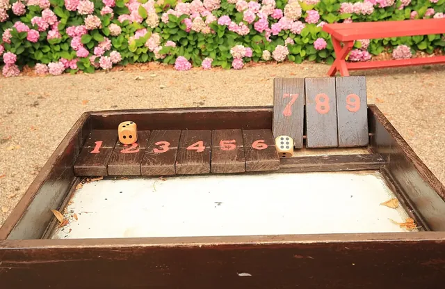 A giant wooden Shut the Box with big number tiles, outdoors in a French garden
