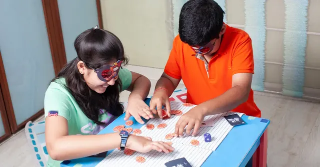 A girl and a boy in decoder glasses playing Super Math Spy at a low table