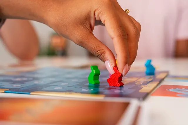A hand moving a red wooden rabbit along the scoring track