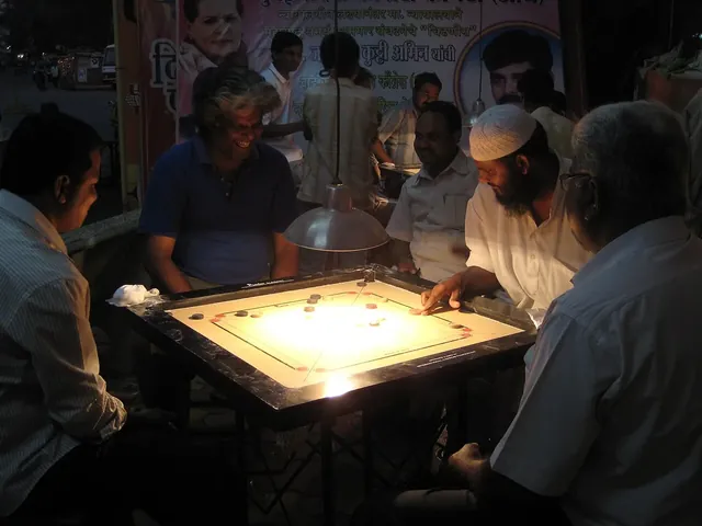 Four men playing carrom at night under a lamp in Andheri, Mumbai, with others watching