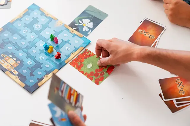 Players' hands laying cards next to the scoring board