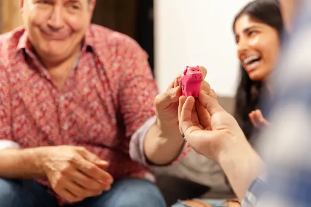 A man handing the squishy pink cow to a laughing woman