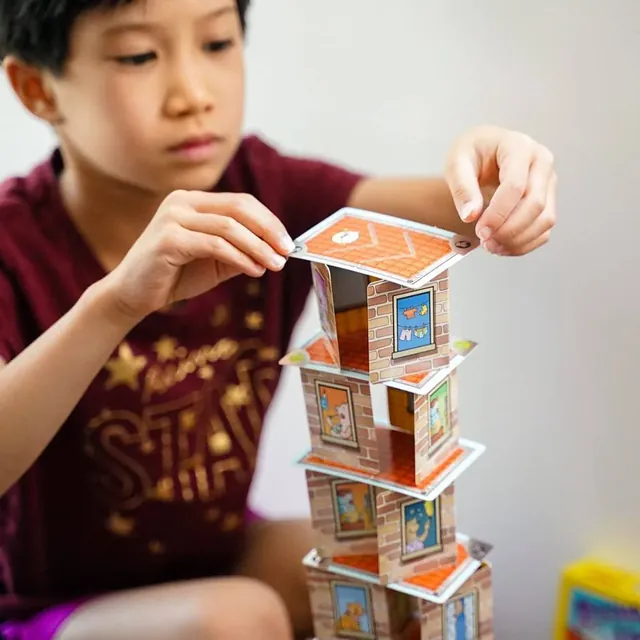 A boy carefully placing a roof card on top of a Rhino Hero tower