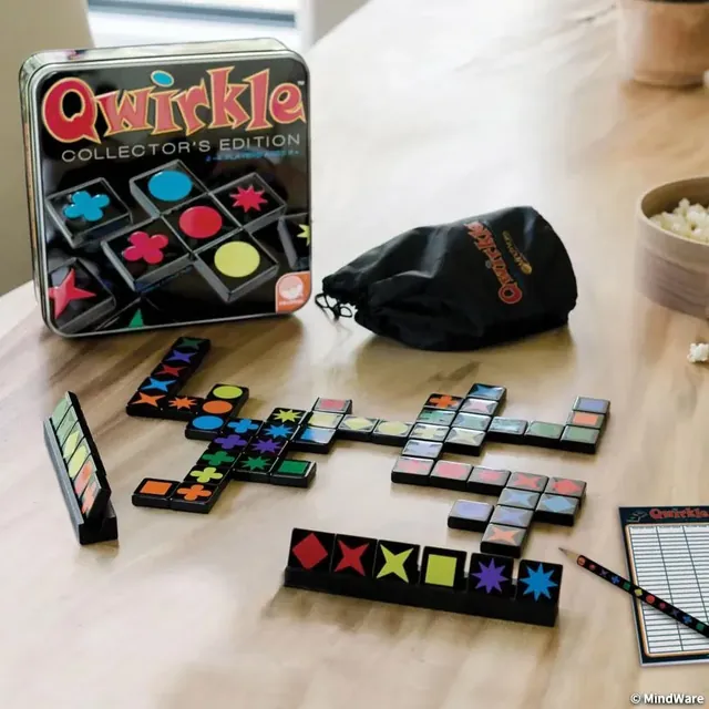 The black Qwirkle Collector's Edition tin with acrylic tiles and racks on a table