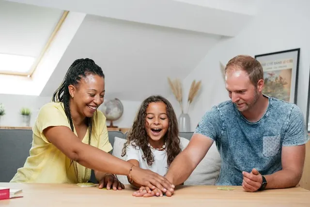 A family slapping their hands onto the pile of cards at a table