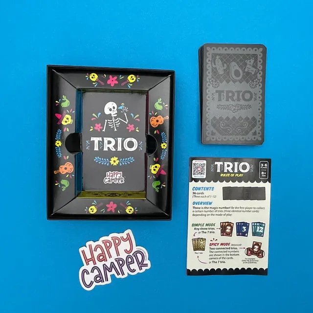 An open Trio box with its card tray, the deck of cards and the rules leaflet on a blue background